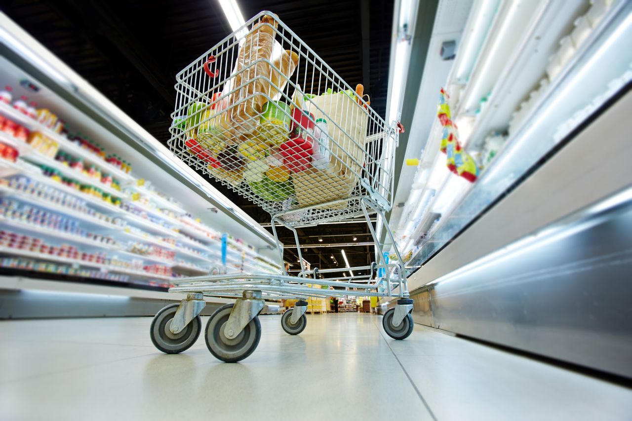 Grocery cart in supermarket aisle.